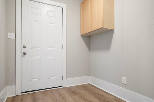 laundry area with wood finished floors and baseboards