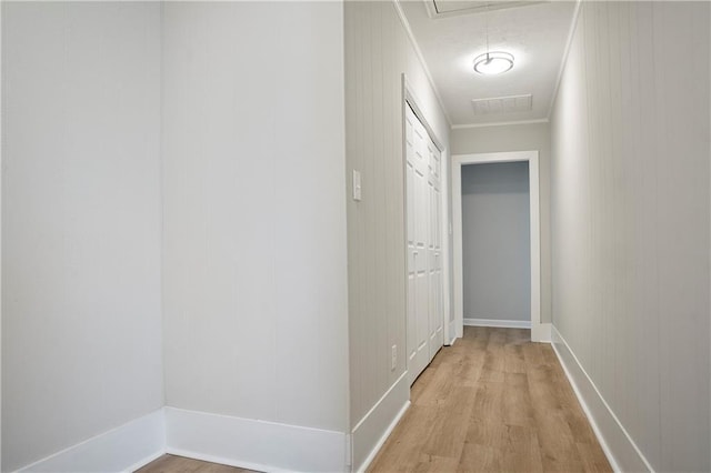 corridor featuring baseboards, visible vents, ornamental molding, and light wood-style flooring