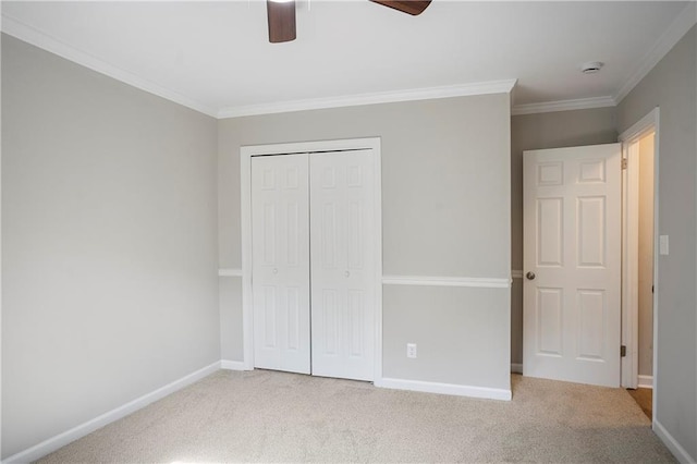 unfurnished bedroom with carpet flooring, baseboards, a closet, ornamental molding, and a ceiling fan
