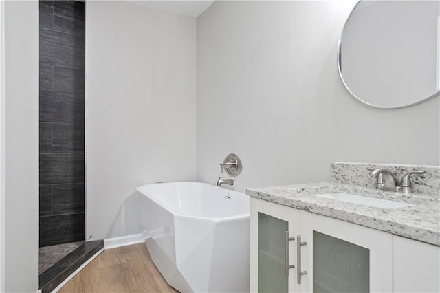 bathroom with a freestanding tub, wood finished floors, and vanity
