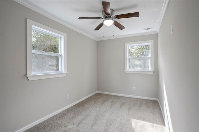 carpeted spare room with ornamental molding, a ceiling fan, visible vents, and baseboards