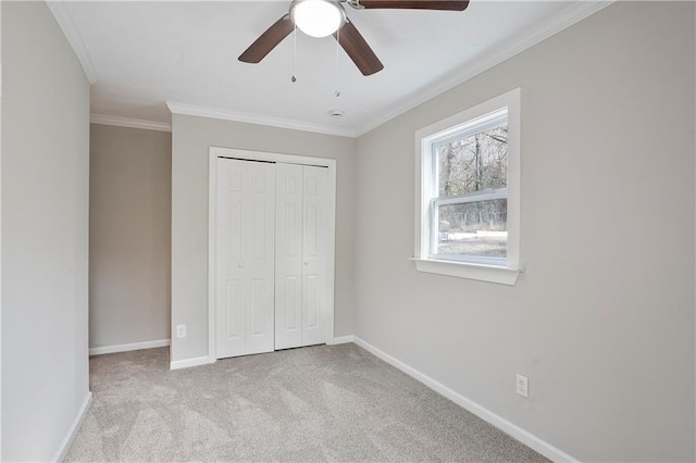 unfurnished bedroom with carpet flooring, ceiling fan, a closet, baseboards, and ornamental molding