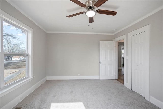 unfurnished bedroom featuring baseboards, crown molding, multiple windows, and carpet