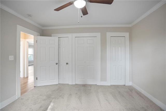 unfurnished bedroom with ornamental molding, two closets, and carpet