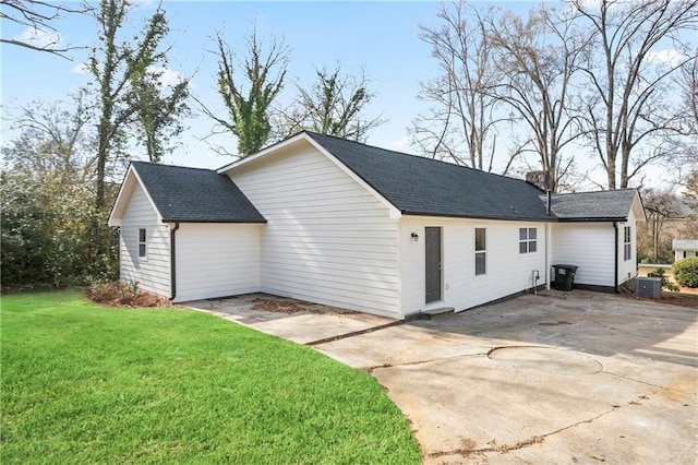 view of side of property with a lawn, central air condition unit, and roof with shingles