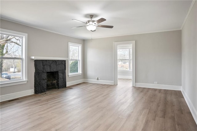 unfurnished living room featuring ceiling fan, light wood finished floors, a stone fireplace, and crown molding