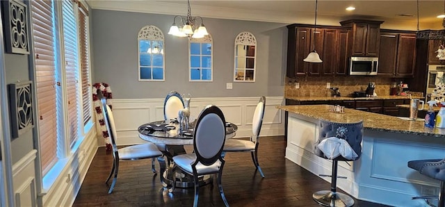 kitchen featuring dark hardwood / wood-style floors, hanging light fixtures, stainless steel appliances, light stone countertops, and dark brown cabinets