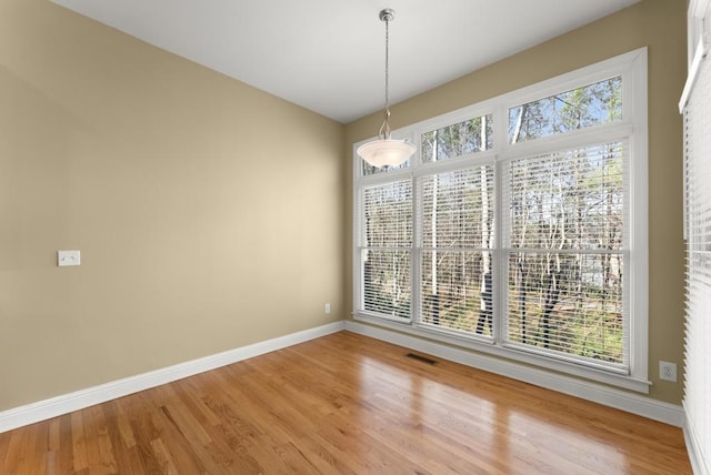 unfurnished dining area featuring light wood-type flooring, visible vents, and baseboards