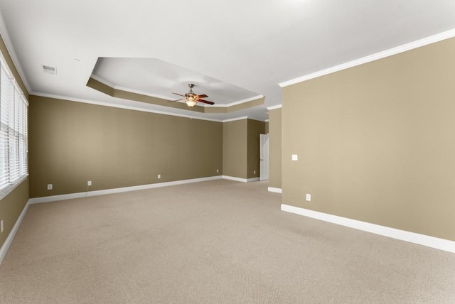 spare room with baseboards, visible vents, a raised ceiling, and crown molding