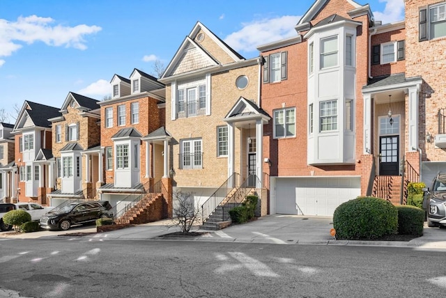 townhome / multi-family property with driveway, a garage, a residential view, and brick siding