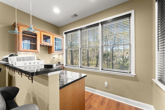 kitchen featuring a peninsula, plenty of natural light, a kitchen bar, and baseboards