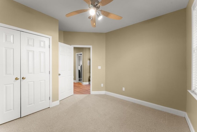 unfurnished bedroom with baseboards, a closet, and light colored carpet