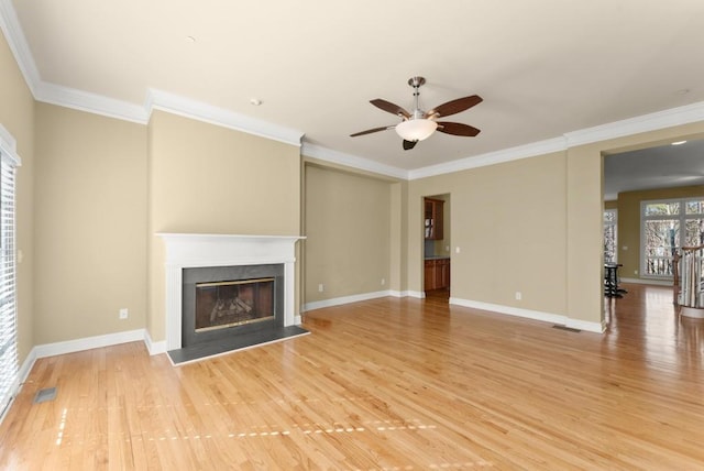 unfurnished living room with light wood-style floors, visible vents, ornamental molding, and a glass covered fireplace