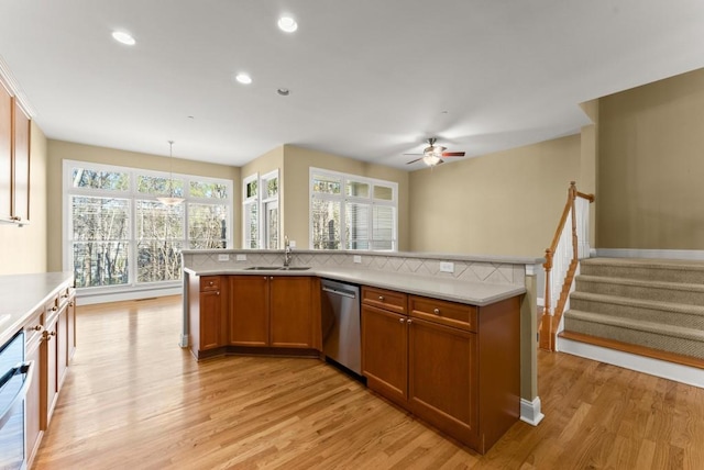 kitchen featuring dishwasher, light countertops, brown cabinetry, and a sink