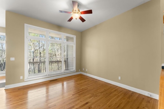 empty room with visible vents, ceiling fan, light wood-style flooring, and baseboards