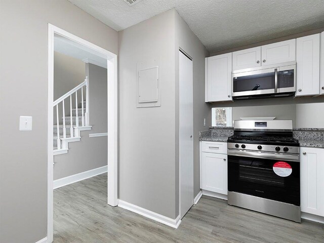 kitchen with white cabinets, appliances with stainless steel finishes, and light stone counters