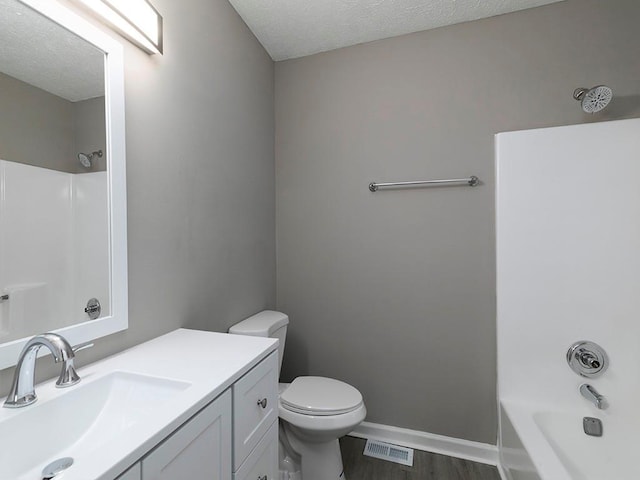 full bathroom with bathing tub / shower combination, a textured ceiling, toilet, vanity, and hardwood / wood-style flooring