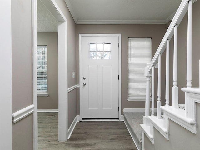 foyer entrance featuring dark hardwood / wood-style floors, crown molding, and a wealth of natural light