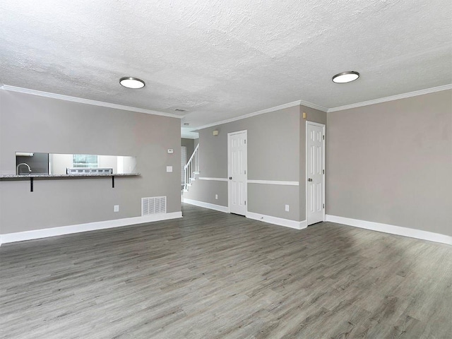 unfurnished living room with dark wood-type flooring, a textured ceiling, and ornamental molding