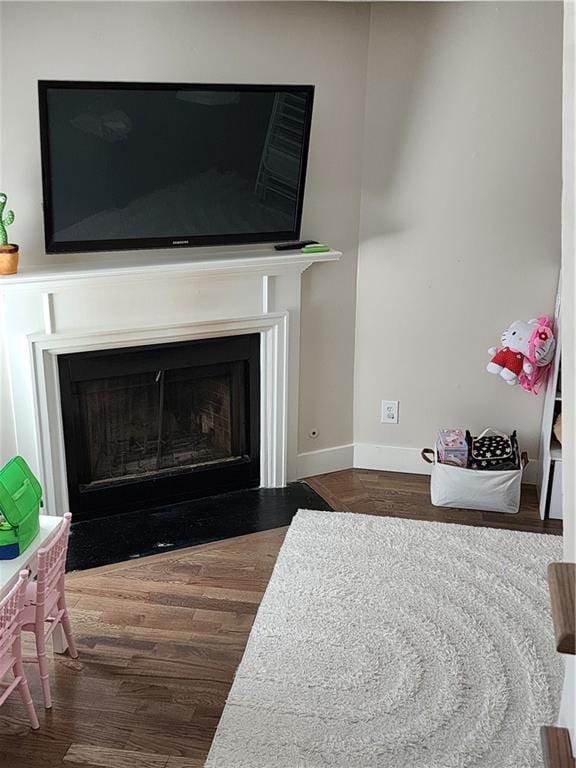 details featuring a fireplace with flush hearth, baseboards, and wood finished floors