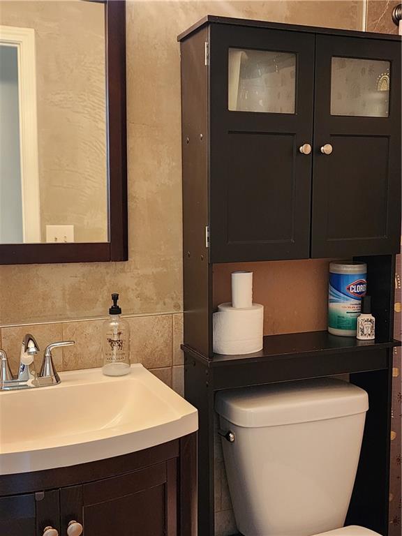 bathroom featuring toilet, tasteful backsplash, and a sink