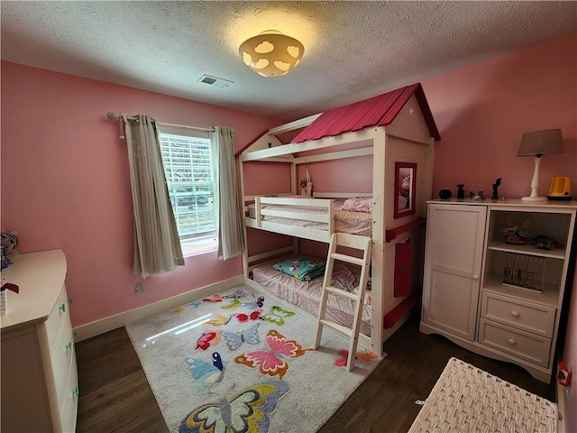 bedroom featuring visible vents, dark wood finished floors, a textured ceiling, and baseboards