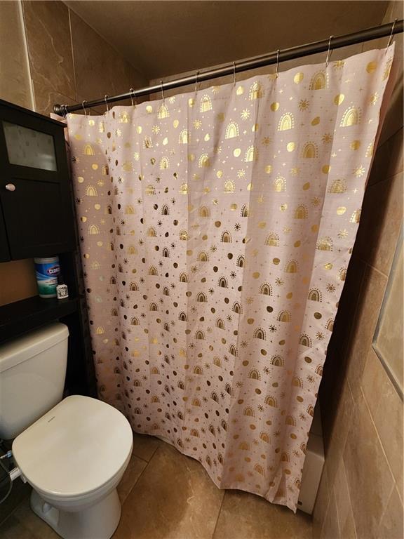 full bath featuring curtained shower, tile patterned flooring, and toilet