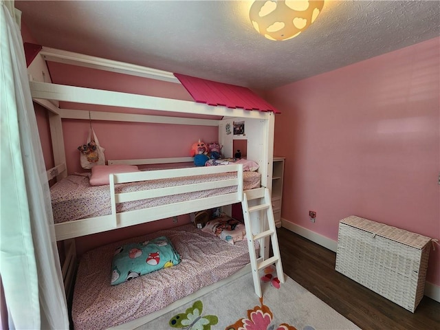 bedroom with a textured ceiling, wood finished floors, and baseboards