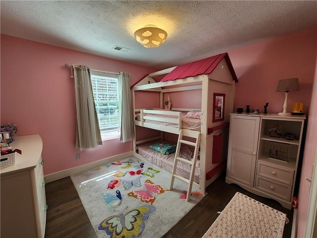 bedroom featuring baseboards, visible vents, dark wood finished floors, and a textured ceiling