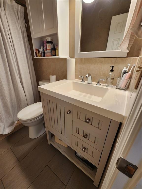 bathroom with toilet, decorative backsplash, wood finished floors, and vanity