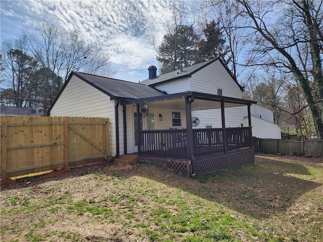 rear view of property with a deck, fence, and a gate