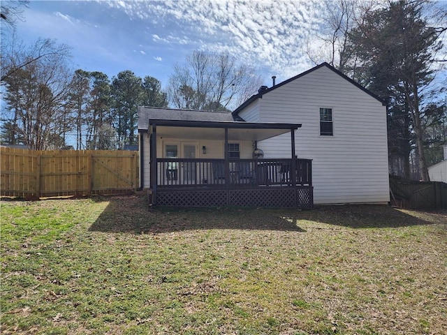 rear view of house with a lawn and fence