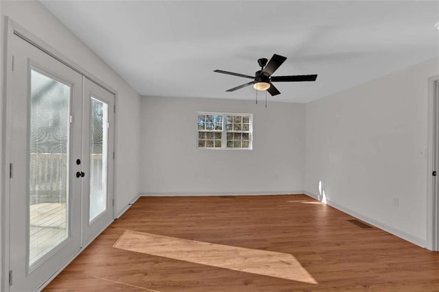 empty room with french doors, wood finished floors, visible vents, and baseboards