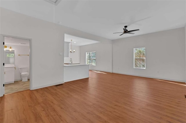 unfurnished living room featuring plenty of natural light, attic access, light wood-style flooring, and a sink