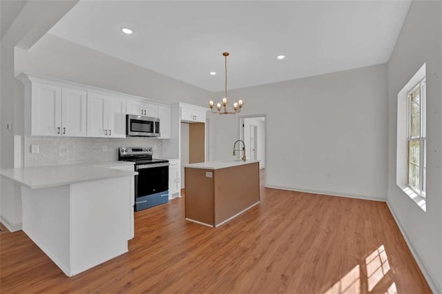 kitchen featuring light wood finished floors, stainless steel appliances, tasteful backsplash, light countertops, and white cabinets