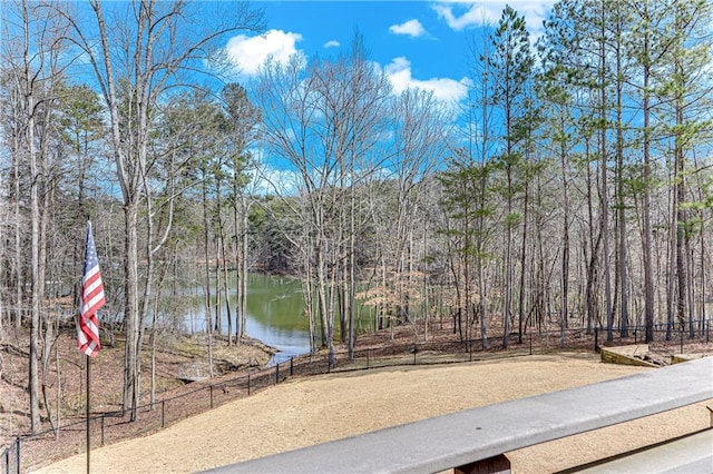 view of water feature featuring fence and a forest view