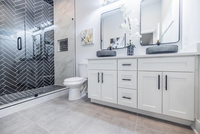 bathroom featuring a shower with door, vanity, toilet, and tile patterned flooring