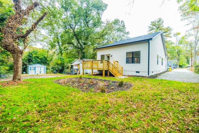 rear view of property featuring a storage shed, a lawn, and a deck