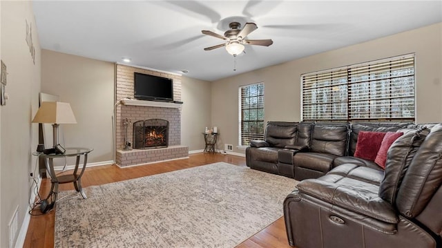 living room featuring a fireplace, light hardwood / wood-style floors, and ceiling fan