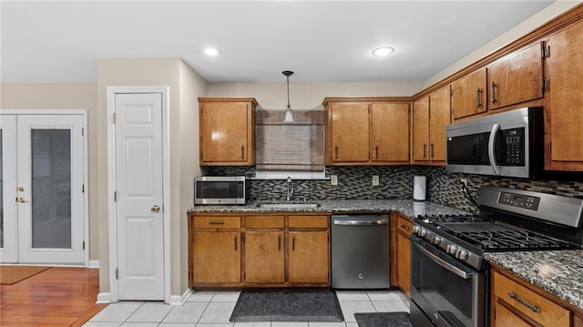 kitchen with appliances with stainless steel finishes, sink, decorative backsplash, and decorative light fixtures