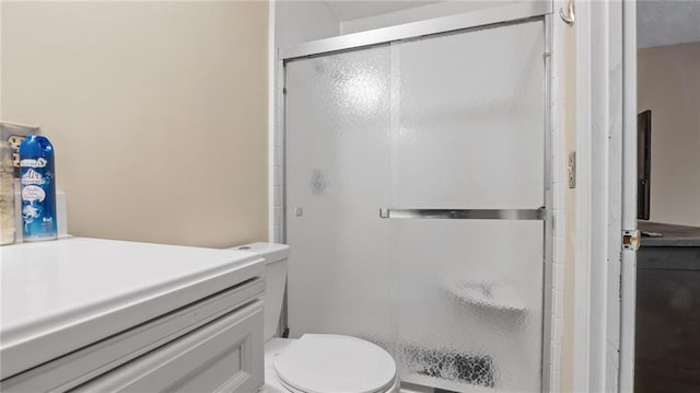 bathroom featuring vanity, a shower with shower door, and toilet