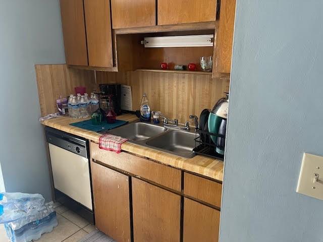 kitchen featuring sink, light tile patterned floors, and stainless steel dishwasher