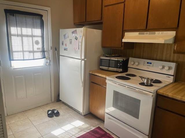 kitchen featuring extractor fan, light tile patterned floors, and white appliances