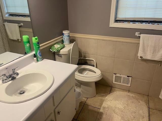 bathroom with vanity, toilet, tile walls, and tile patterned flooring