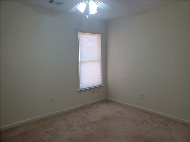 carpeted spare room featuring plenty of natural light and ceiling fan