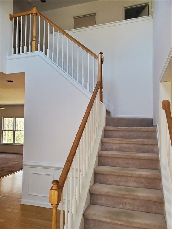 stairway with hardwood / wood-style flooring and a towering ceiling