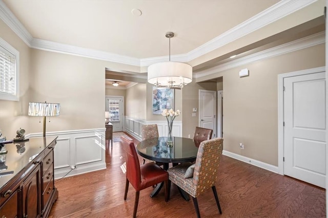 dining space with crown molding, a chandelier, wood finished floors, and wainscoting