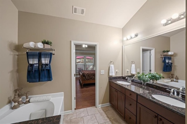 ensuite bathroom with a sink, visible vents, and a tub