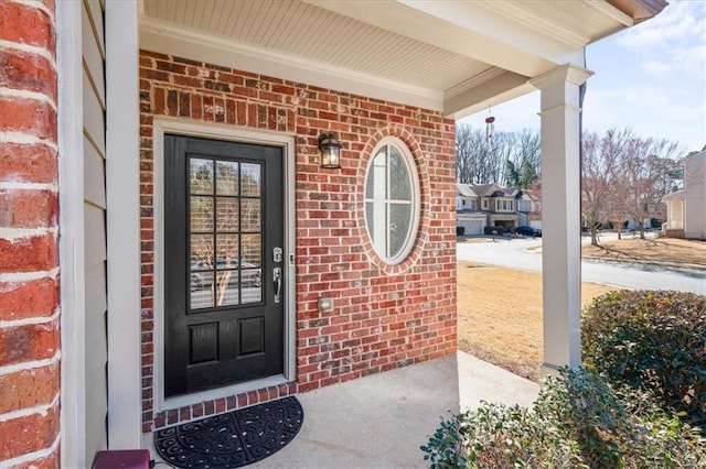 entrance to property with a porch and brick siding