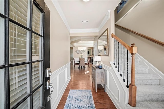 entrance foyer with visible vents, wainscoting, dark wood-type flooring, crown molding, and a decorative wall